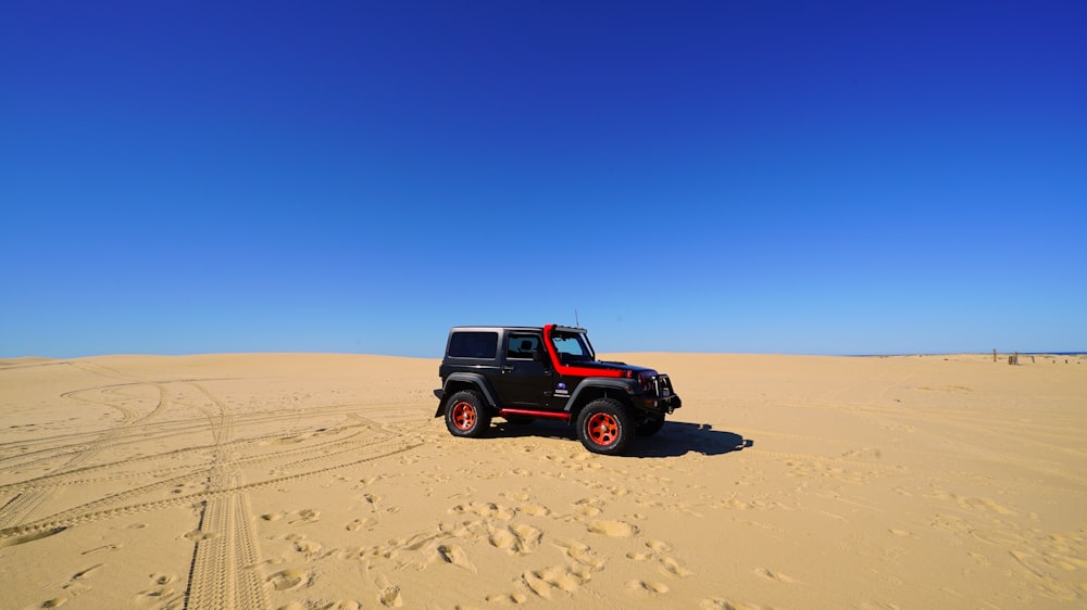 SUV preto e vermelho viajando no deserto durante o dia