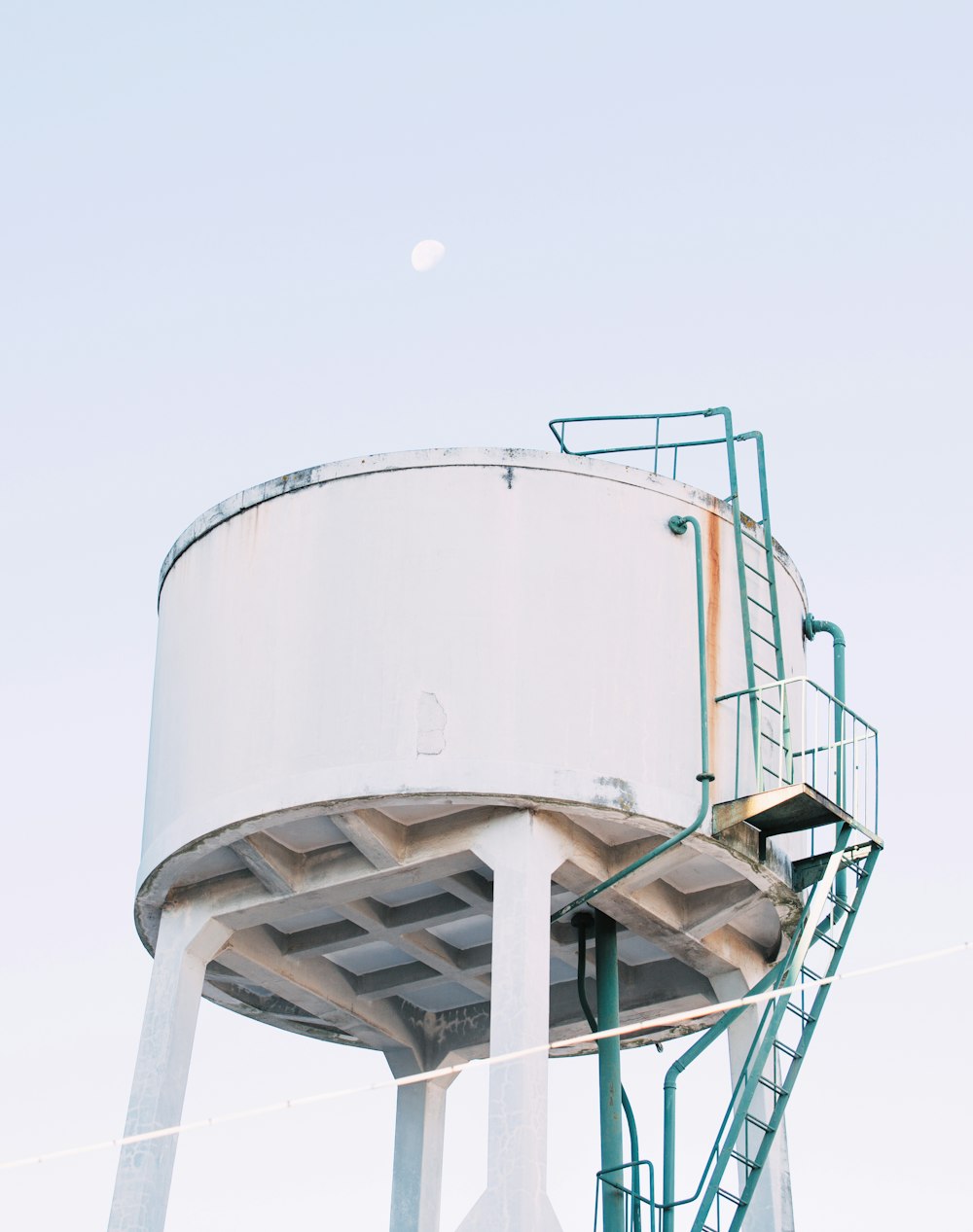 large round white concrete fluid tank with green metal ladder