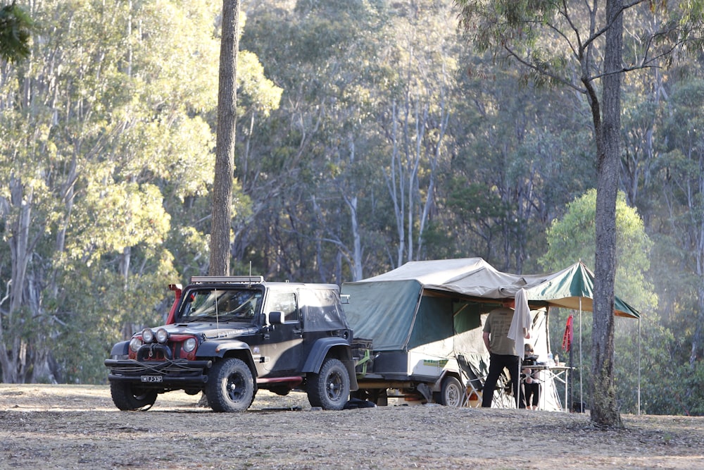 black SUV with pop-up camper surrounded by forest