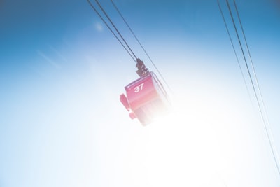 red cable car under clear sky snowbound teams background