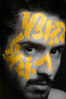 Close-up of hands coloring a detailed melanin-rich face design with warm gold and deep brown tones.
