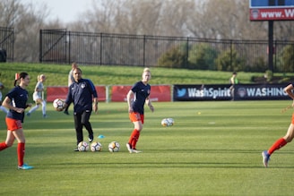 A lively football training session with young players practicing drills under a coach's guidance on a sunny field.