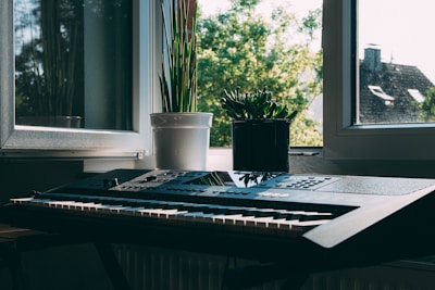 A serene studio corner with a keyboard, sheet music, and a small potted plant bathed in natural light.