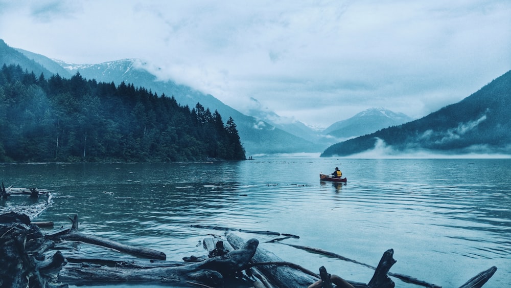 person riding canoe in the middle of lake