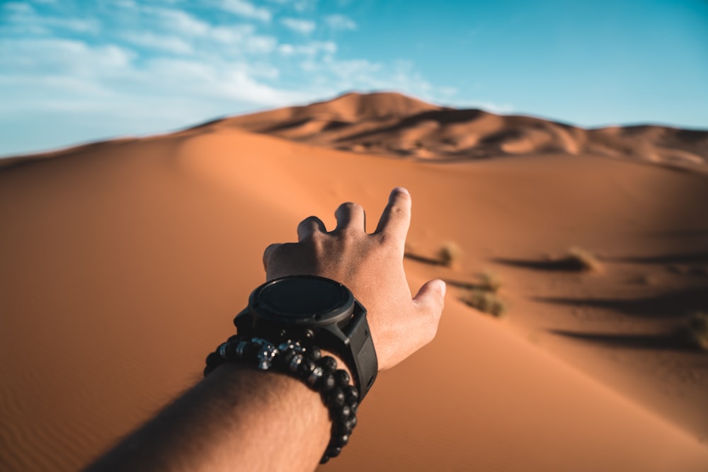 Person, die tagsüber auf die Wüstendüne zeigt