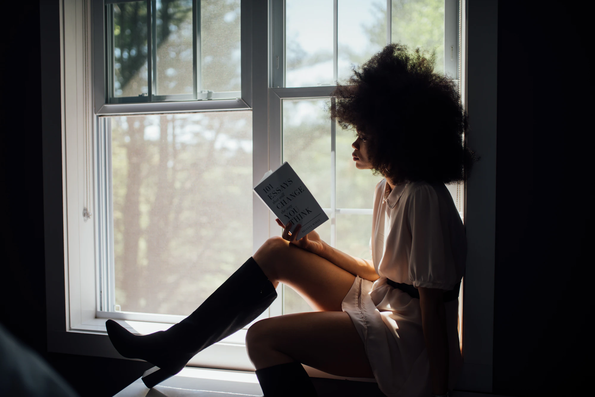 A woman reading by a sunlit window