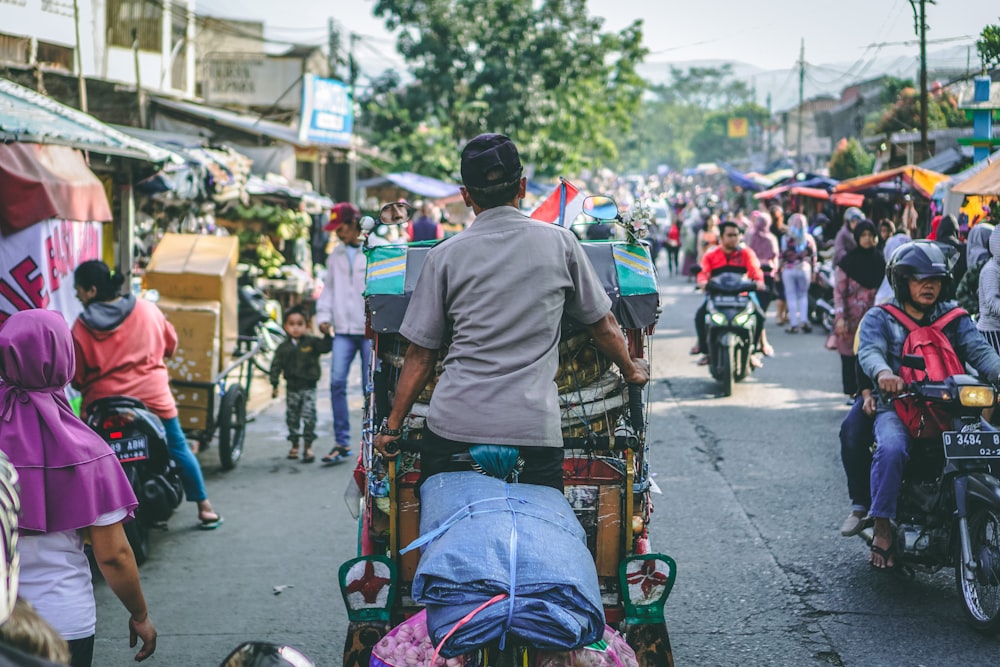 selective photography of man pedaling wagon