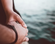 selective focus photo of person holding hands near body of water