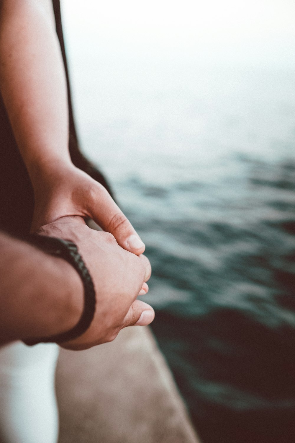 selective focus photo of person holding hands near body of water