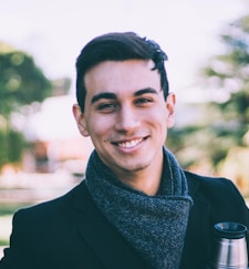 smiling man standing near green tree