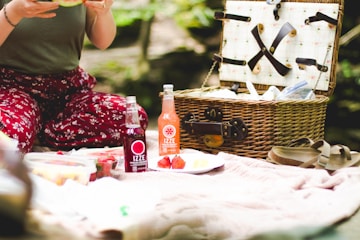 picnic basket beside two Ezze bottles on blanket