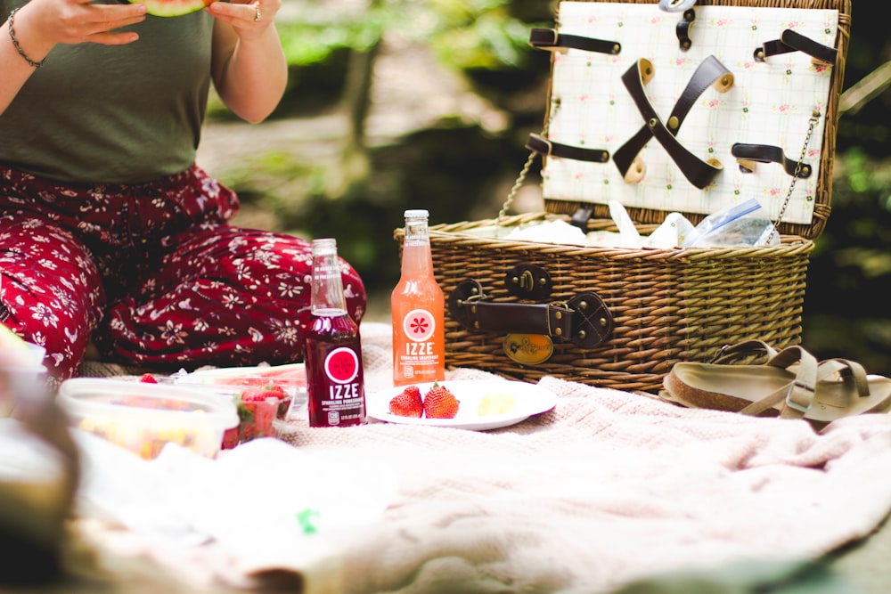picnic basket beside two Ezze bottles on blanket