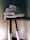 A stack of neatly folded white towels sits atop a wooden stool with a natural finish. The background is softly lit, creating a cozy and serene atmosphere.