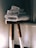 A stack of neatly folded white towels sits atop a wooden stool with a natural finish. The background is softly lit, creating a cozy and serene atmosphere.