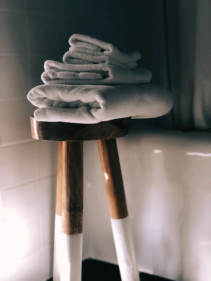 Serviettes éponge blanches pliées sur un tabouret en bois