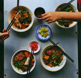 person's hand using chopsticks on bowl of noodles