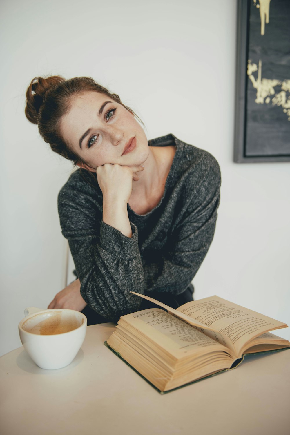 brown-haired woman in black sweater near brown book
