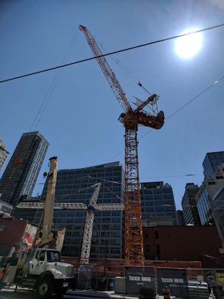 A modern construction site with towering cranes and workers coordinating under a clear sky.