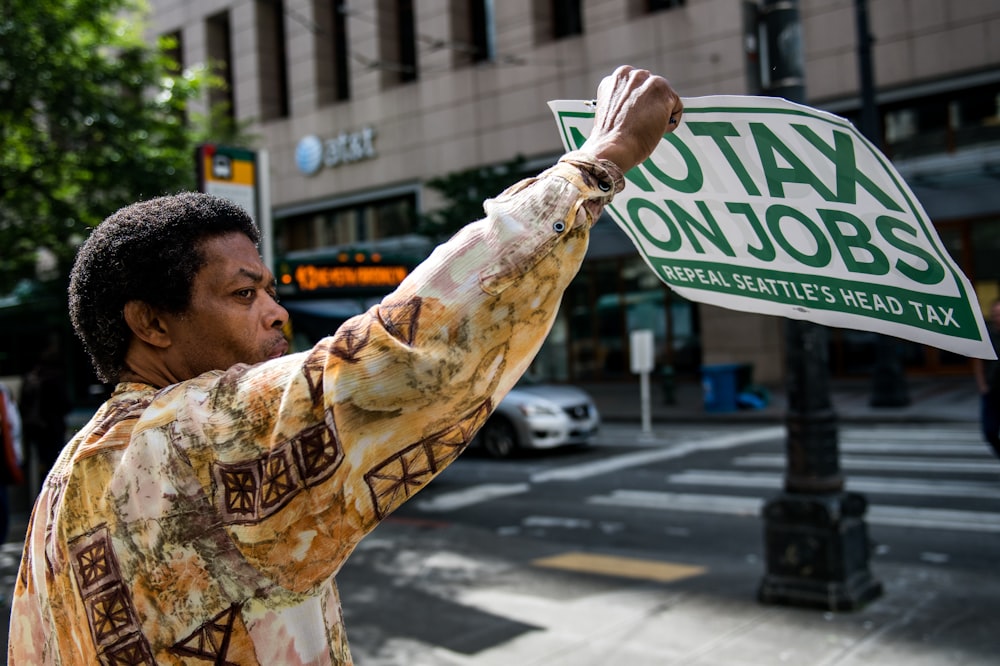 person holding white and green poster