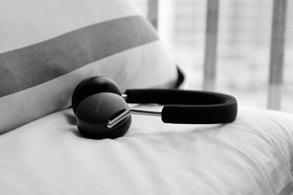 grayscale photography of full size wireless headphones on textile