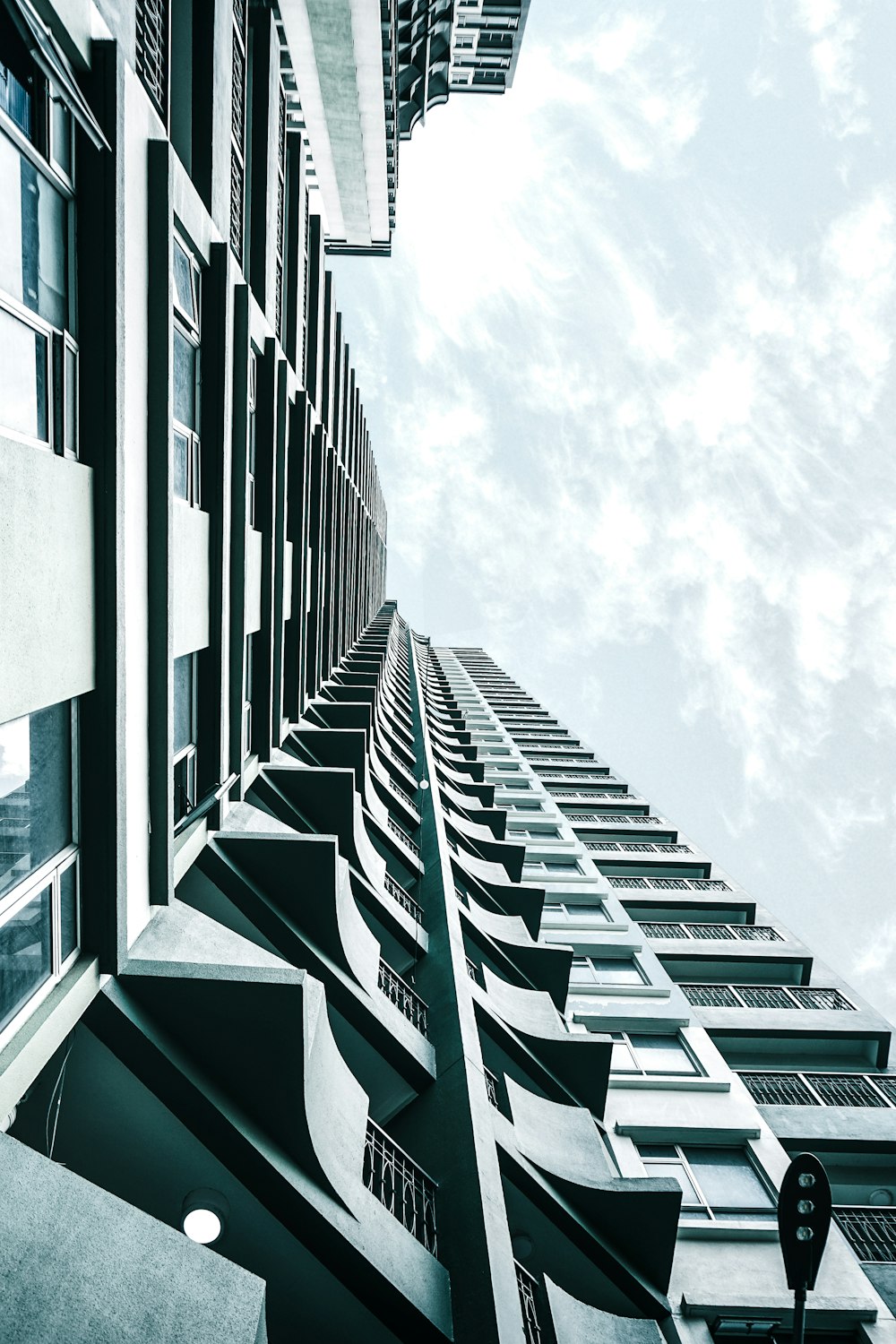 Fotografía de ángulo bajo de un edificio de hormigón gris bajo nubes blancas durante el día