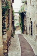 narrow pathway surrounded by concrete of buildings