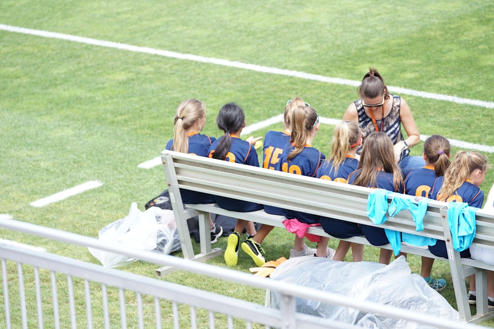 eight girls sitting on gray bench