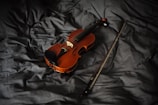 A violin resting on a polished wooden stage under soft spotlight lighting.