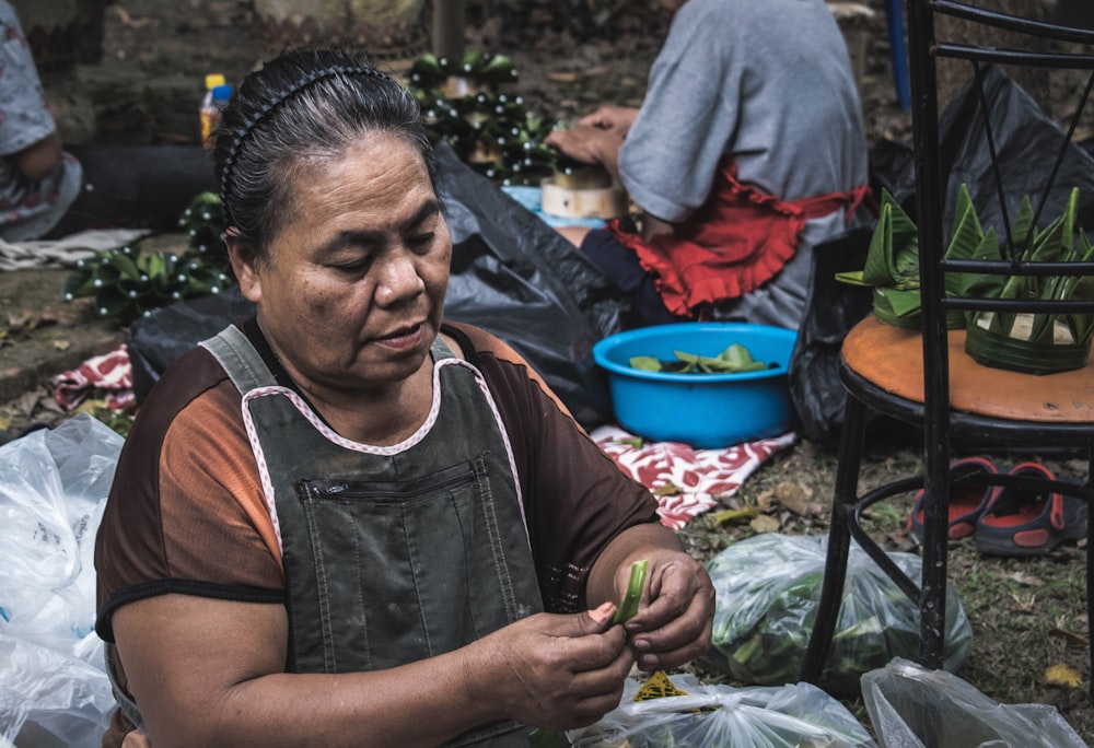 woman holding green vegetable near chair and pack