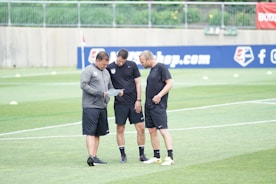 three men standing on football field