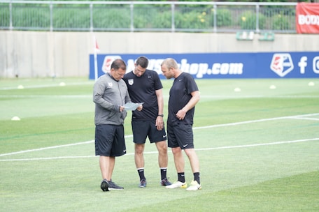 three men standing on football field