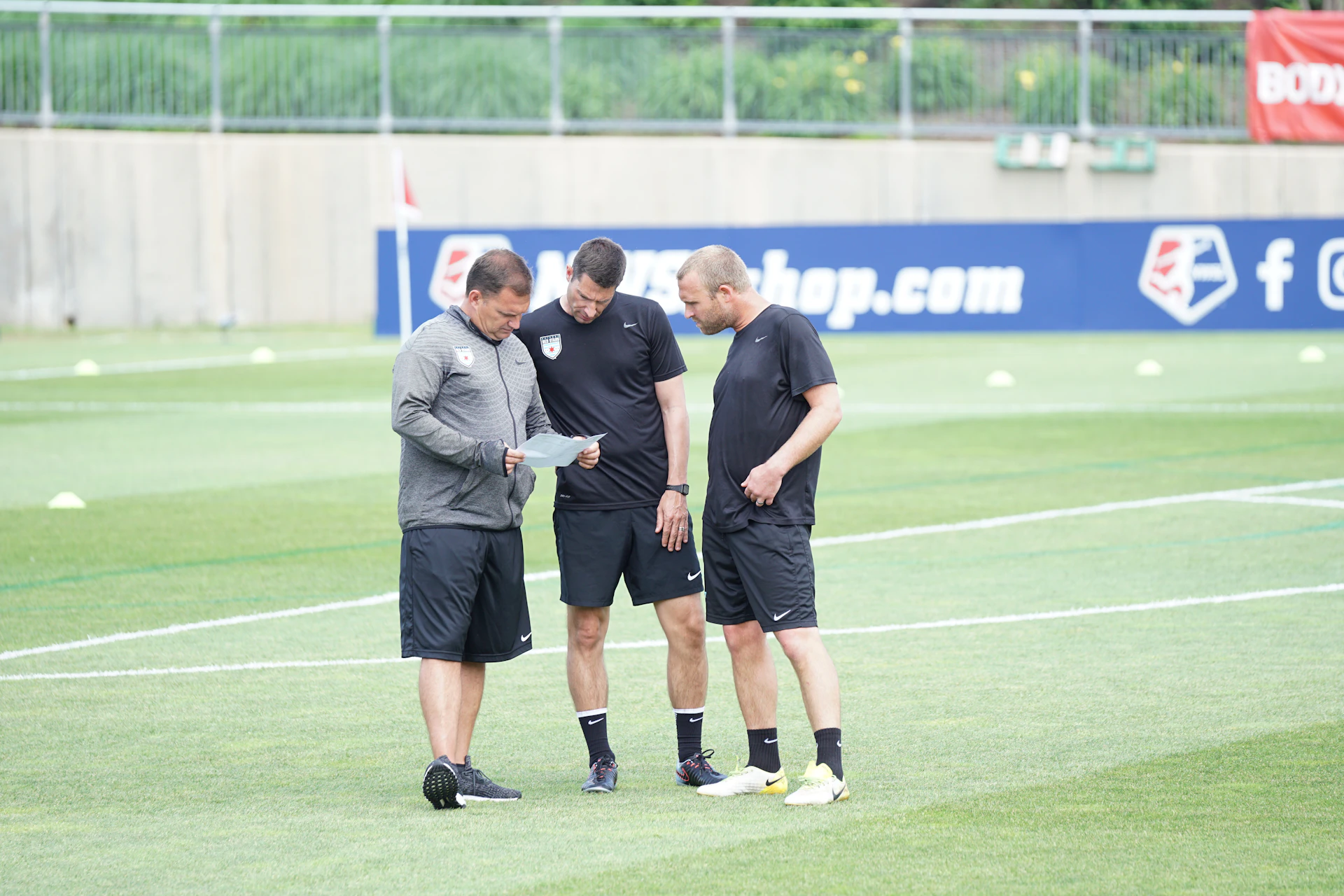 Three men standing on football field.