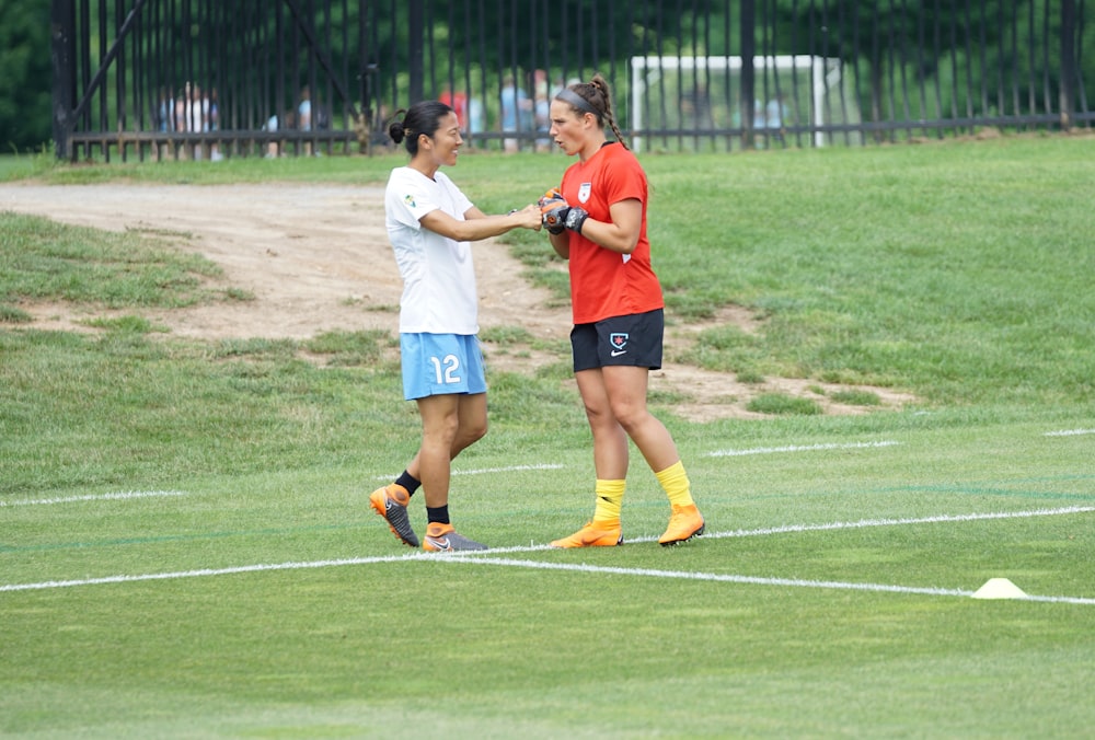 two women fist bumping on field