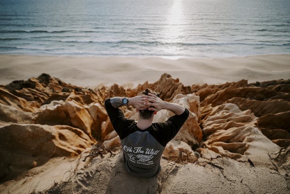 man sitting on clip of rock mountain