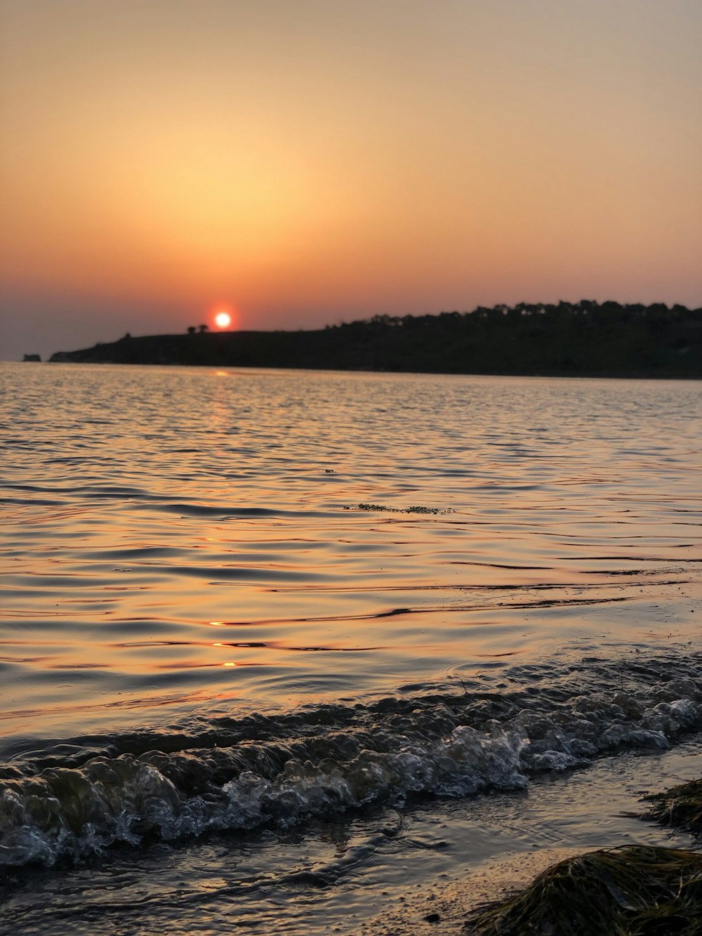body of water near island at sunset