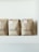 Three brown paper coffee bags with labels sit on a white shelf. The bags are from Primo Passo Coffee Co.