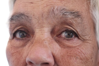 A close-up shot showing the intense gaze of an elderly woman, highlighting her wrinkles and stories.