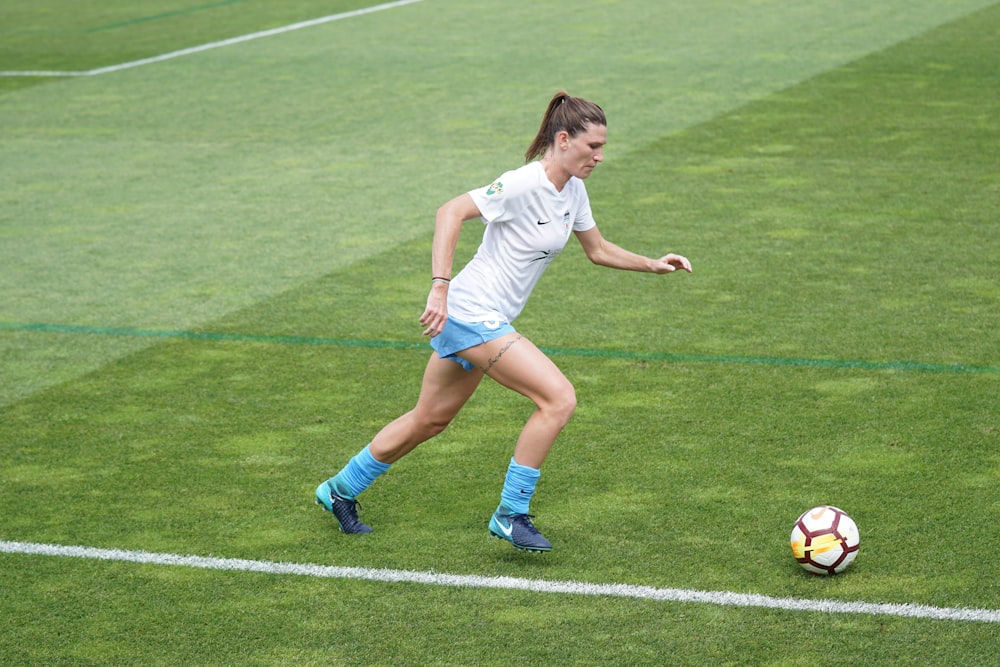 Mujer en el campo de fútbol botando la pelota de fútbol durante el día