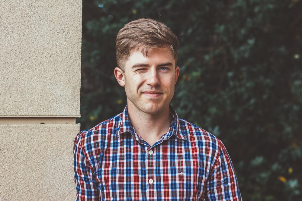 man standing beside wall winking