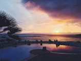 A vibrant sunset casting colors over a tranquil resort pool.