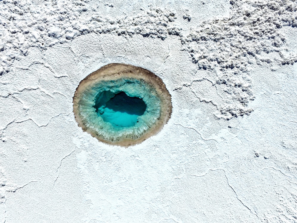 a blue hole in the white sand of a beach