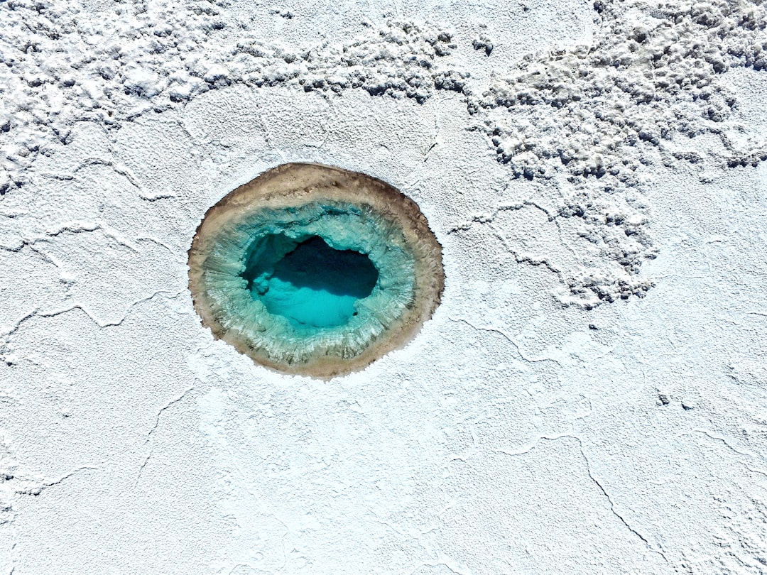 a blue hole in the white sand of a beach, San Pedro Atacama