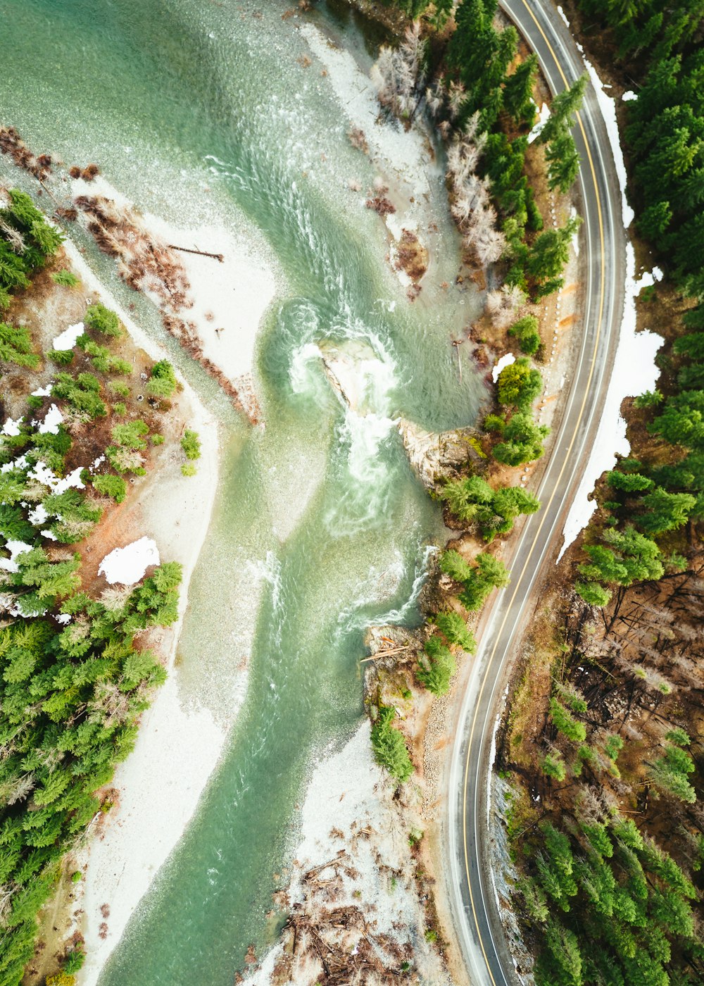 Fotografía aérea de la carretera de asfalto vacía en el lado de la colina cerca del río durante el día
