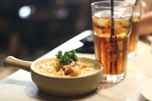 A cozy lunch setting with a bowl of creamy chicken bacon ranch pasta alongside a glass of iced tea