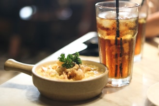 A cozy lunch setting with a bowl of creamy chicken bacon ranch pasta alongside a glass of iced tea