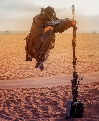 person in overall suit holding rod floating on desert field