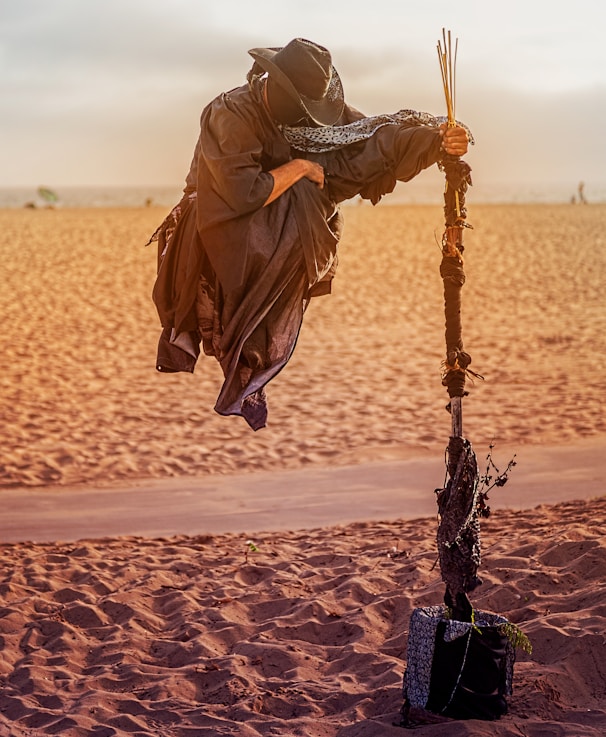 person in overall suit holding rod floating on desert field