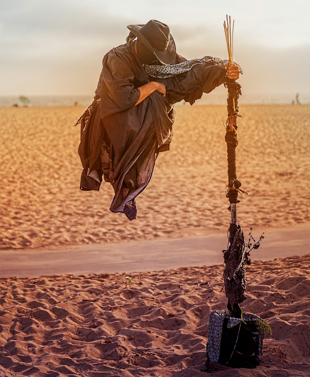 person in overall suit holding rod floating on desert field