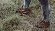Close-up of sturdy riding boots stepping on a grassy trail.