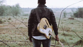 man holding brown guitar